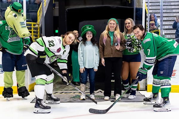 Kids stand on the ice with hockey players and a mascot during a St. Baldrick’s event.