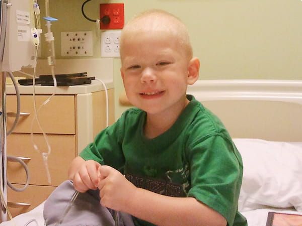Young child smiling while sitting in a hospital room.