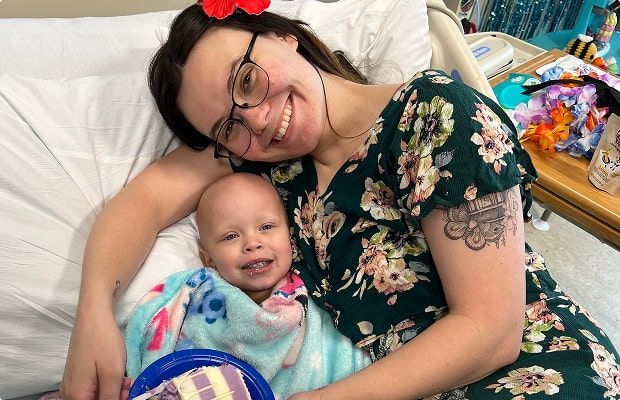 Lilah smiling in a hospital bed with her mom beside her.