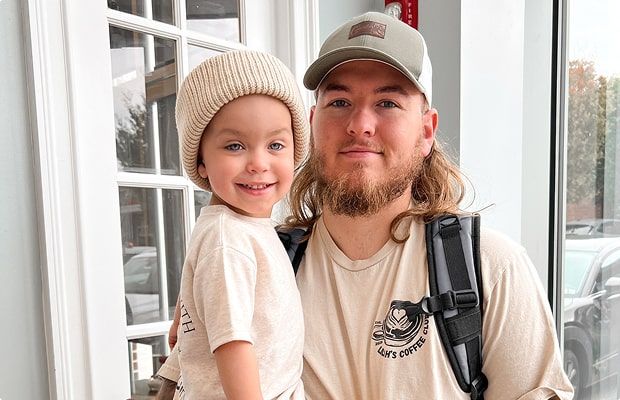 Lilah being held by her dad, both smiling at the camera.