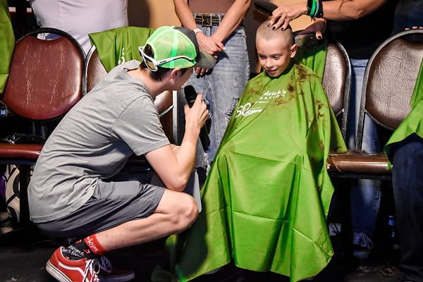 An emcee talks with a child during a head-shaving event.