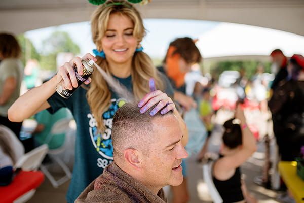 A volunteer doing a participant’s hair at a St. Baldrick’s event.