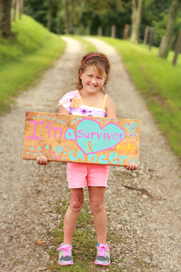 Chloe holding a cancer survivor sign