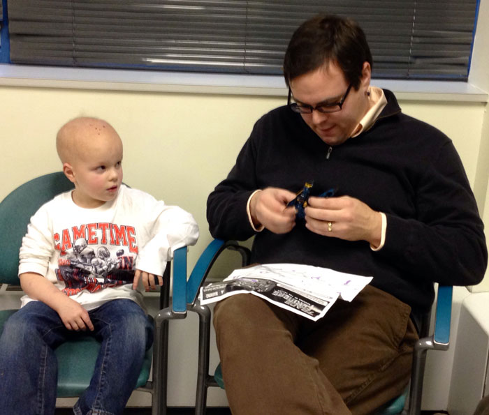 Chase looks on skeptically as his father attempts to assemble a Transformer in the waiting room.