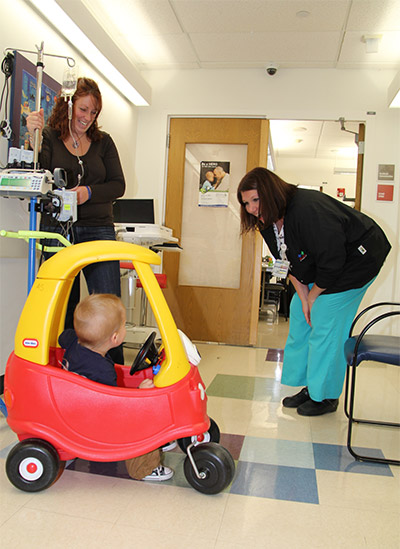 Kelly Clickner talks to a patient driving a Fisher Price car