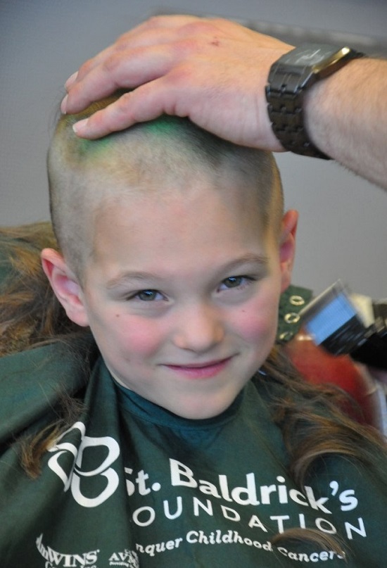 Young boy shaving head for cancer