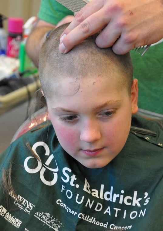 Boy looking pensive as his head is shaved