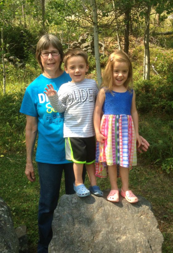 Anne stands with her grandchildren in the woods