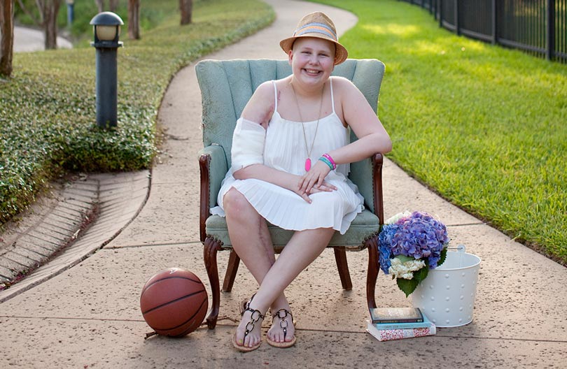 Caroline sitting outside with her radiant smile and a few of her favorite things