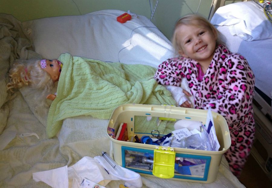Quincy plays with her doll in a hospital bed