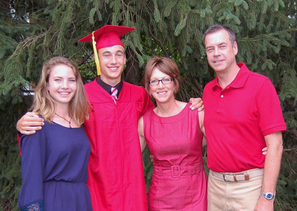 Aaron sports a cap and gown and stands with his parents and sister