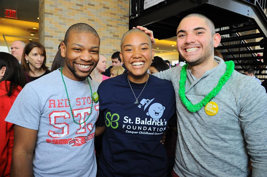 College students smiling after shaving their heads together