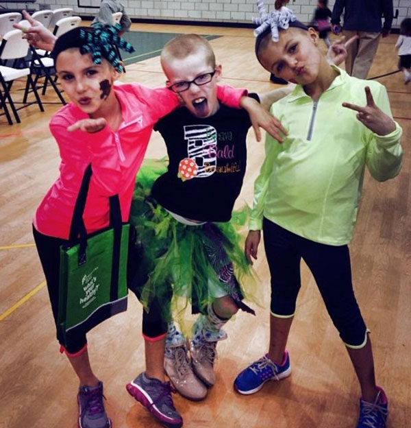 Three girls rock their bald heads after they braved the shave for childhood cancer research.