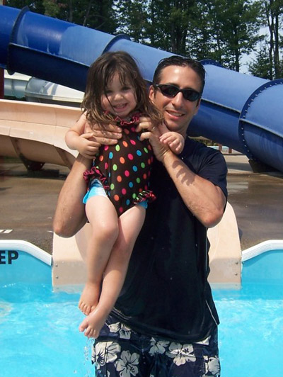 Mike holds a laughing Juliana in a pool before she was diagnosed with childhood cancer