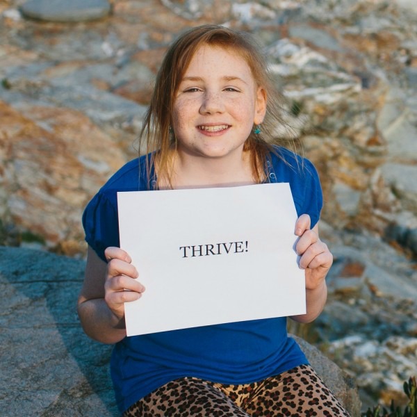 Grace holds a sign that reads 'thrive'