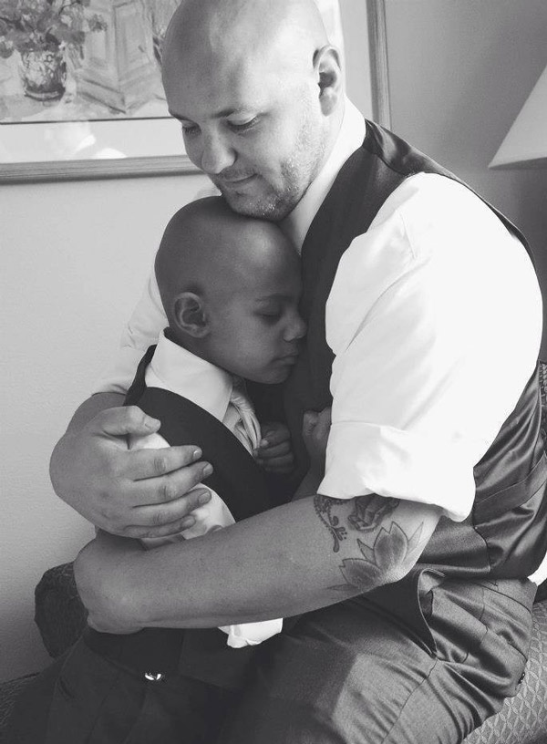 Stepdad hugging stepson in treatment for childhood cancer