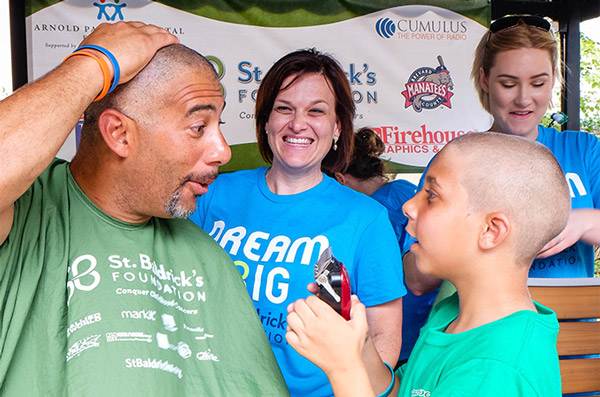 Greg gives his son a surprised look after being shaved bald during a St. Baldrick's event