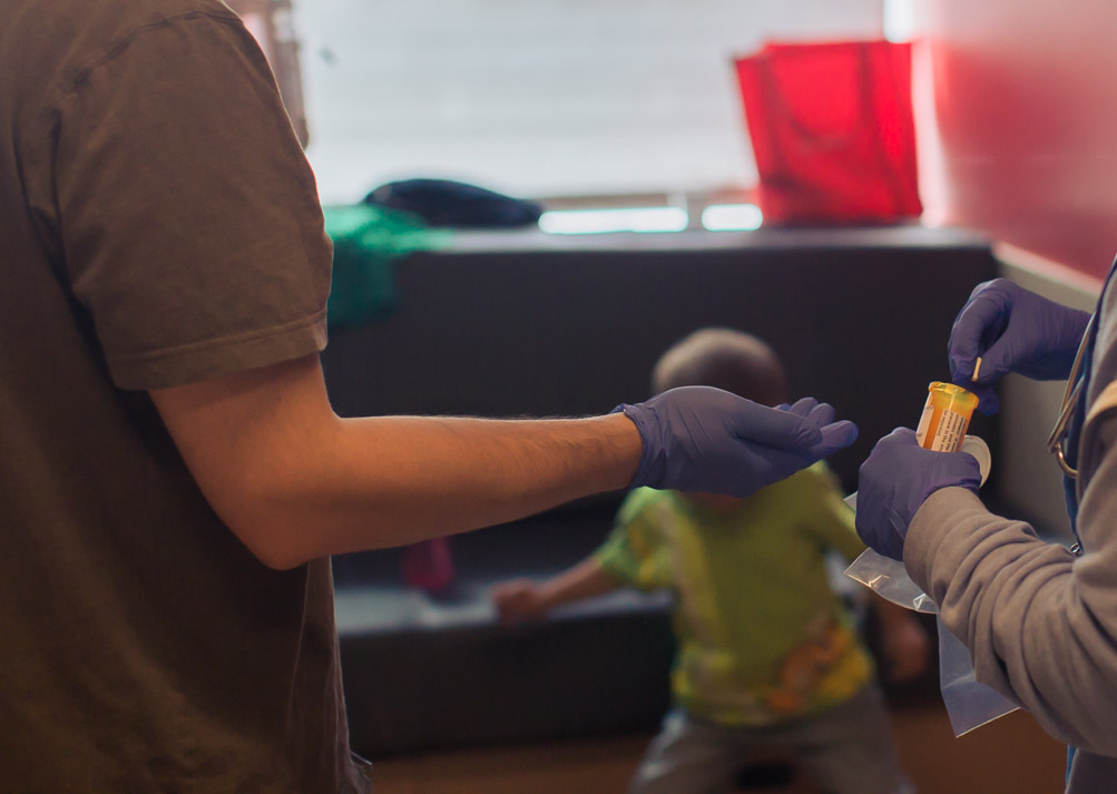 A nurse hands pills to Micah