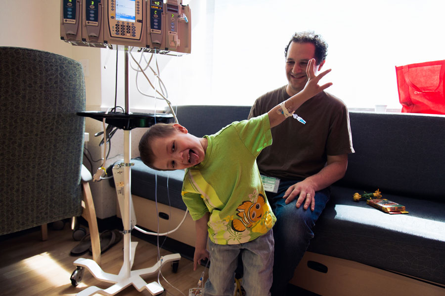 Micah sticks out his tongue and clowns around in his hospital room