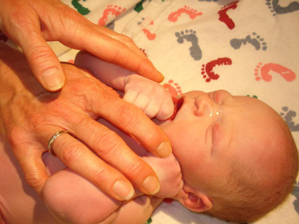 Ellie's mom's hands resting on newborn baby Chase
