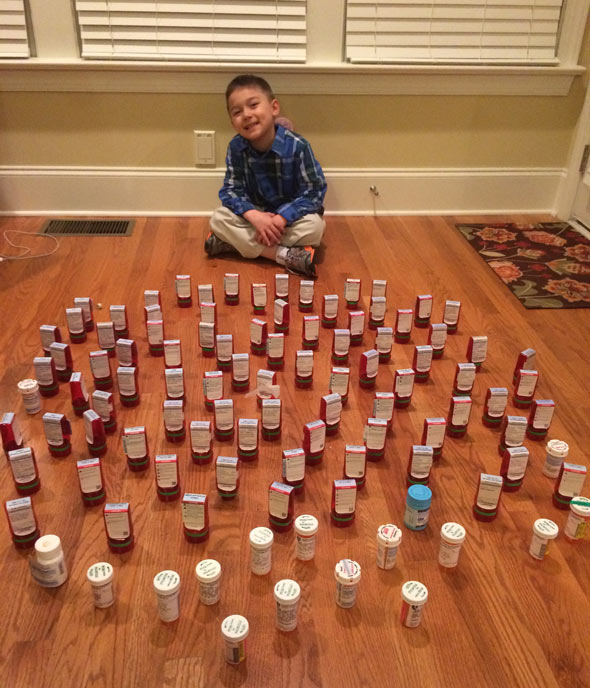 Scott sits with all the empty pill bottles from his acute lymphoblastic leukemia treatment