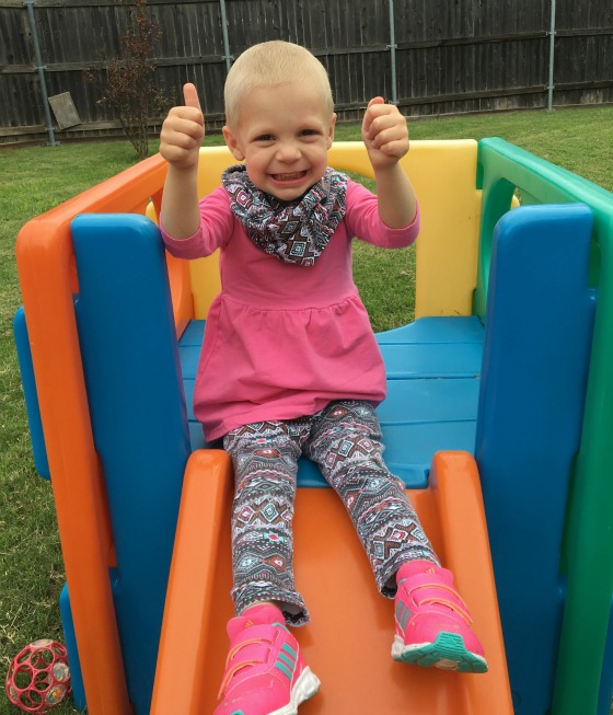 Avery gives a thumbs up while sitting on a slide