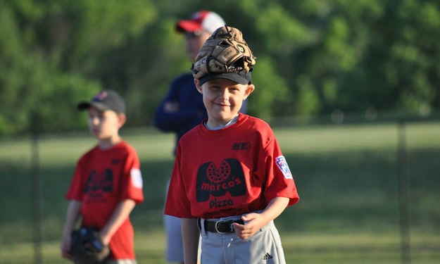 Holden smiles with a baseball glove on his head