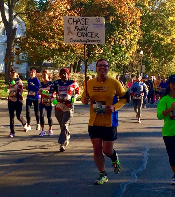 Bob holds a sign while he runs to 'chase away cancer'