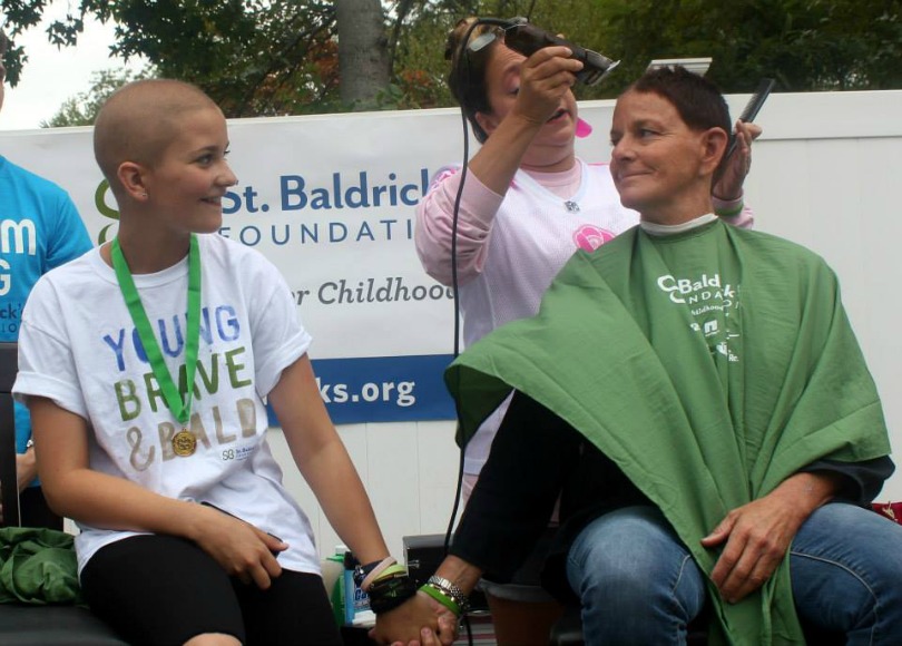 Daphne holds her mom's hand as she shaves for St. Baldrick's