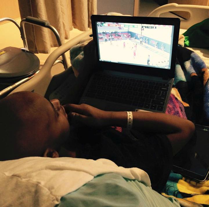 Tori watches a basketball game on a laptop in bed