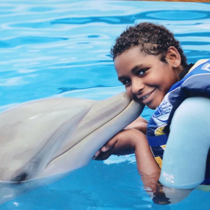 Tori smiles next to a dolphin