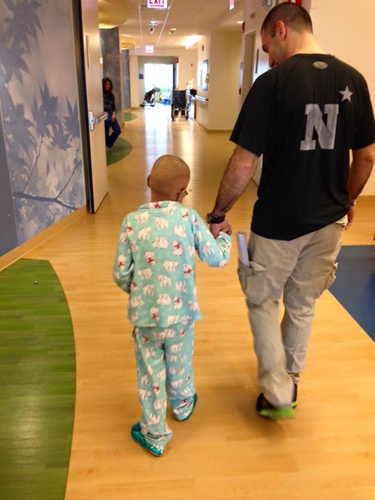 Abby and her dad walk down the hospital hallway holding hands