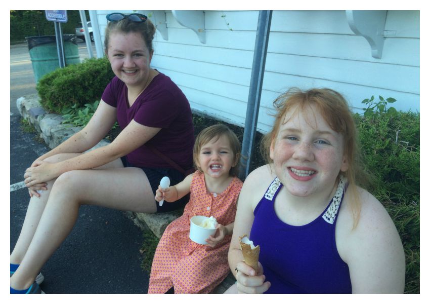 Grace smiles while eating ice creme with her sisters