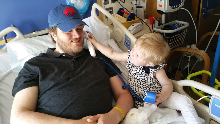 Father and child play in a hospital bed