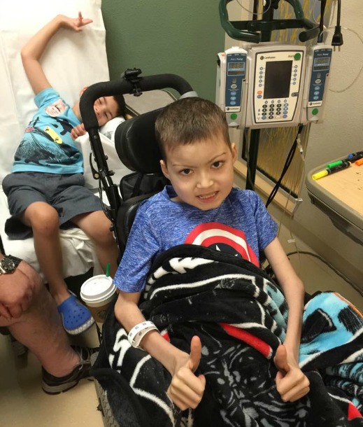 Brayden goofs off behind Julian during a hospital visit