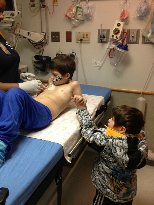 Brayden holds Julian's hand during a procedure
