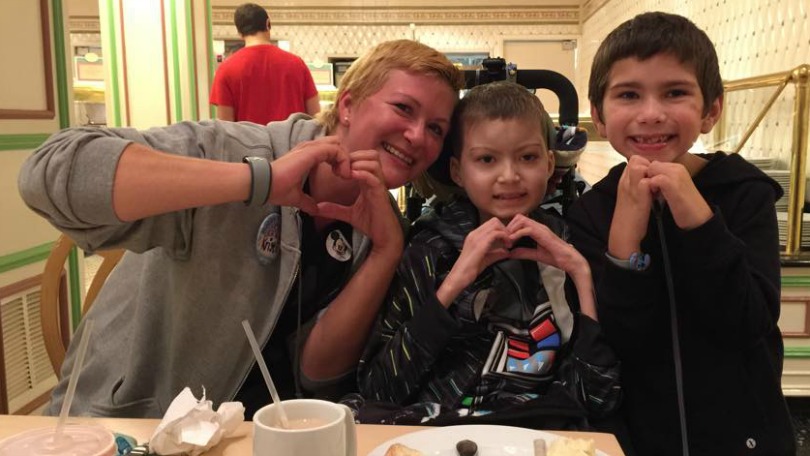 Kristi, Julian, and Brayden make hearts with their hands during Julian's Disney trip