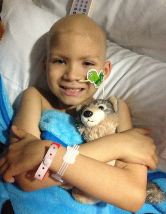 Julian smiles while hugging a stuffed dog at the hospital