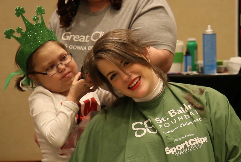 Abby makes the first swipe over Ambassador Sarah's head with the clippers