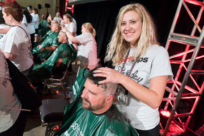 Barber smiles while shaving a head