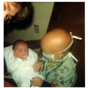 Young Andrew wearing a face mask with his baby brother