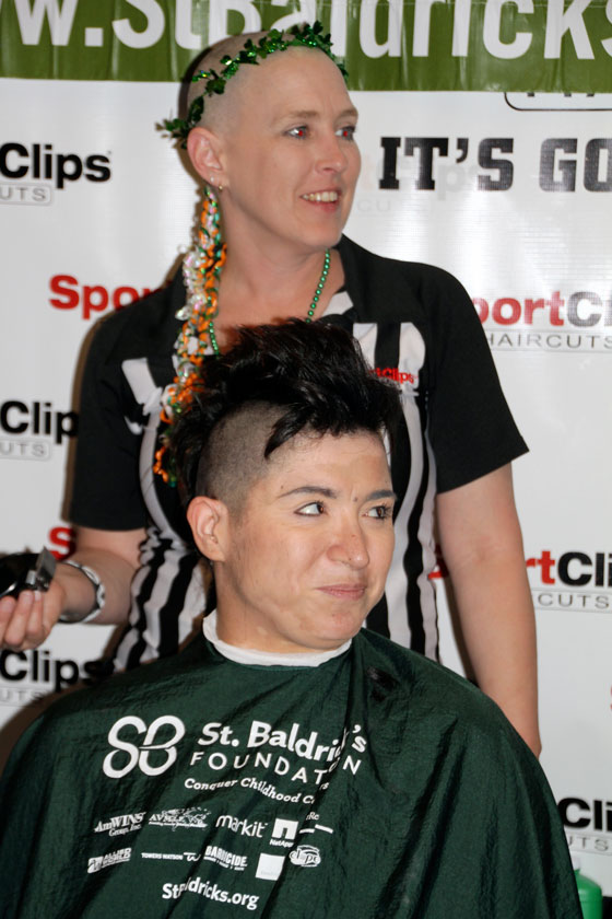 A bald Keli shaves another supporter's head
