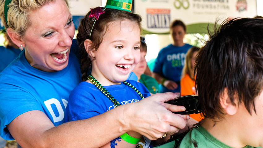 Woman shaving head for cancer at St. Baldrick's event