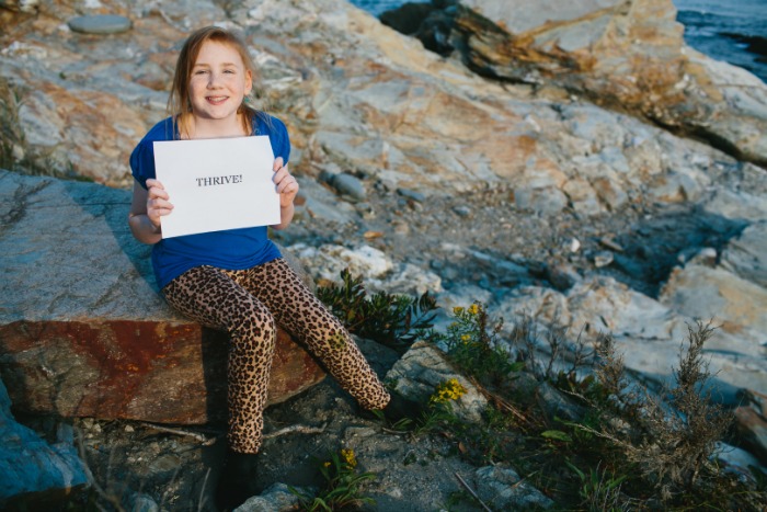 Grace holds a sign that reads, Thrive