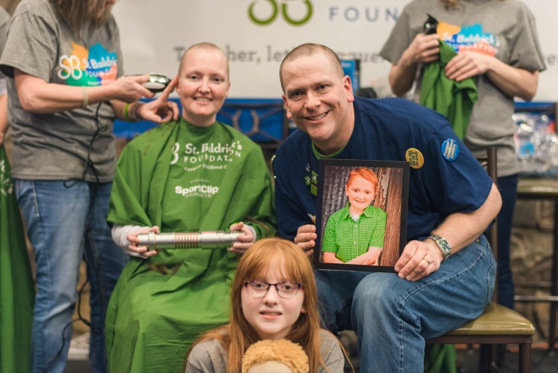 Ian's family holds a photo of the boy during their shave