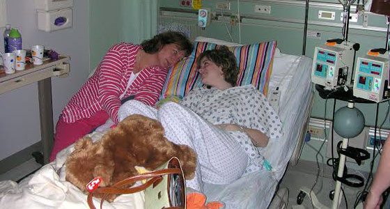 Sarah and her mom laying on her hospital bed