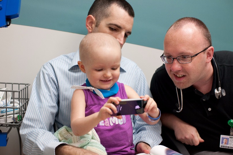 Dr. Nalepa plays on a cellphone with a young patient