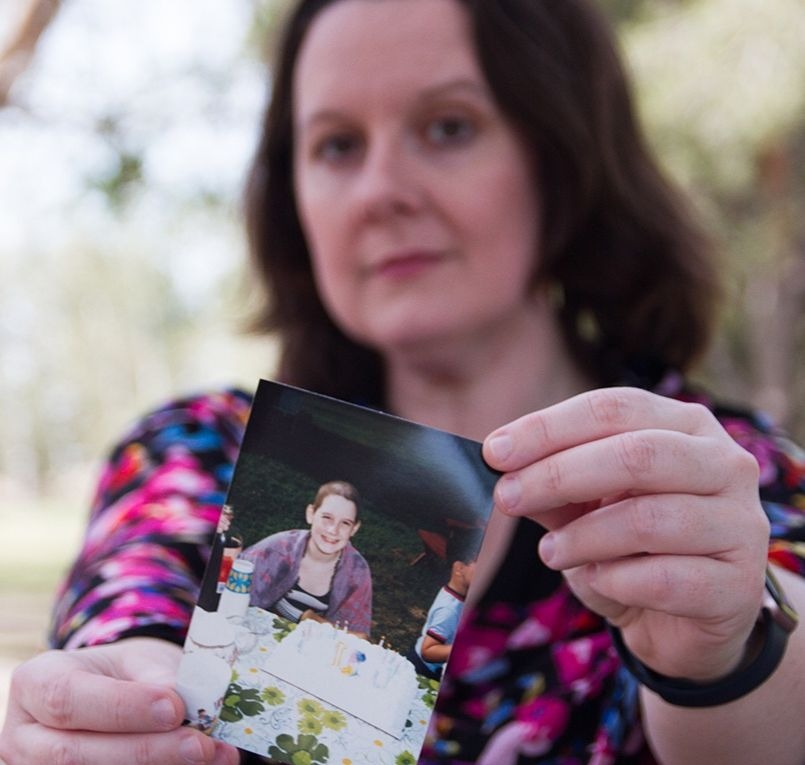 Nora holding a photo of herself when in treatment