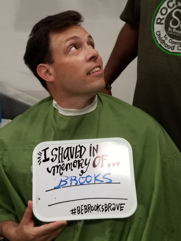 Brian shaves while holding a sign that reads: Brooks