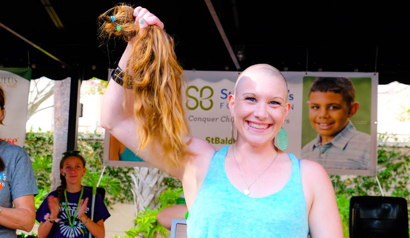 Woman holding a ponytail of hair at a St. Baldrick's event